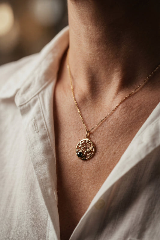 Close-up of a person wearing a gold necklace with a circular pendant.